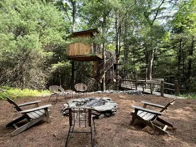 a group of chairs and a tree house in the woods at Eco-Friendly, Abstract Treehouse Surrounded by Wildlife and Hiking Trails For a Special Getaway in Sparrow Bush, New York in Sparrow Bush