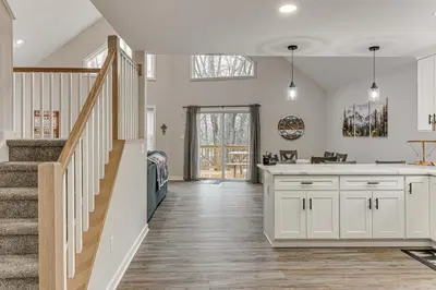 a kitchen with white cabinets and a staircase at Lake and Pool Access Poconos Family Getaway! in Albrightsville
