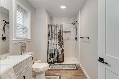 a white bathroom with a toilet and a shower at Lake and Pool Access Poconos Family Getaway! in Albrightsville