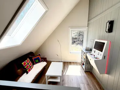 a attic living room with a couch and a tv at Pocono Chalet,Hot Tub,Arcade,Fireplace, Lake,Pool, Pet friendly, near Jim Thorpe No extra fees to use amenities in Towamensing Trails