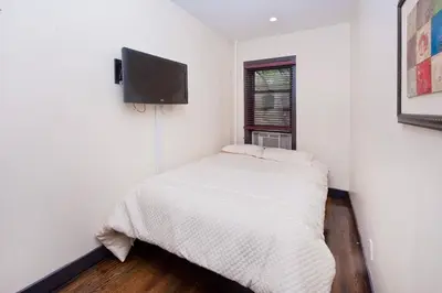 a white bedroom with a bed and a flat screen tv at The Ideal II Vibe 8558 in New York