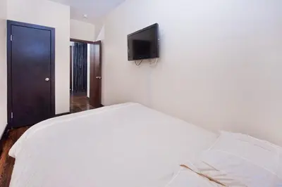 a bedroom with a white bed and a flat screen tv at The Ideal II Vibe 8558 in New York