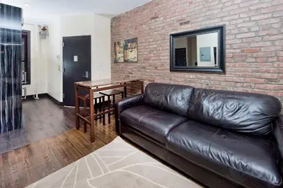 a living room with a leather couch and a brick wall at The Ideal II Vibe 8558 in New York