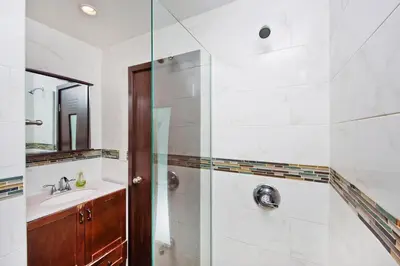 a bathroom with a shower with a sink and a mirror at The Ideal II Vibe 8558 in New York