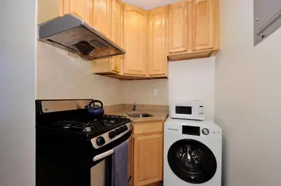a small kitchen with a stove and a refrigerator at The Gram V Vibe 8615 in New York