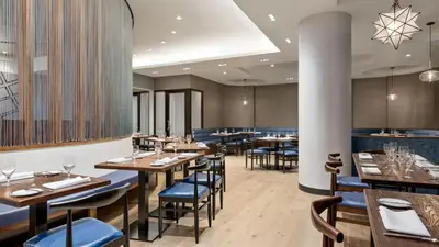 a restaurant with wooden tables and blue chairs at The Vibe on 5th Vibe 8750 in New York