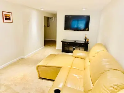 a living room with a yellow couch and a flat screen tv at Beautiful Lakefront Chalet in the Poconos! in Hawley