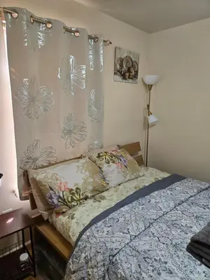a bedroom with a bed and a curtain with flowers at Honey queen room 5 in Newark