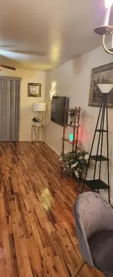 a living room with wooden floors and a flat screen tv at Honey queen room 5 in Newark
