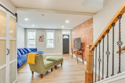a living room with a blue couch and a brick wall at Family-Friendly Townhome with Patio in Columbia! in Columbia