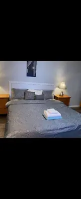a bed with a blue comforter with a book on it at Lemon king room 4 in Newark