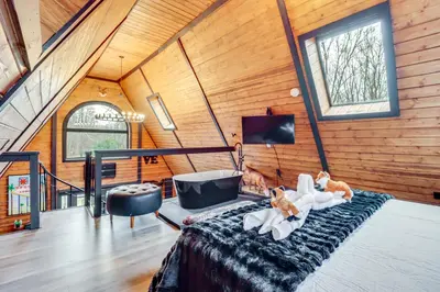 a room with a bed and a tv and windows at 9 Mi to Big Boulder Mtn A-Frame Cabin with Hot Tub in Albrightsville