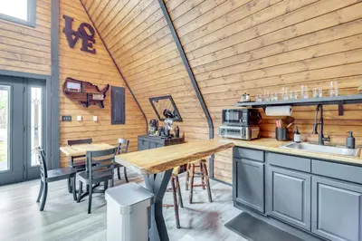 a kitchen with wooden walls and a wooden table and chairs at 9 Mi to Big Boulder Mtn A-Frame Cabin with Hot Tub in Albrightsville