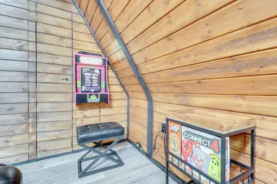a room with a television and a stool in a wooden wall at 9 Mi to Big Boulder Mtn A-Frame Cabin with Hot Tub in Albrightsville