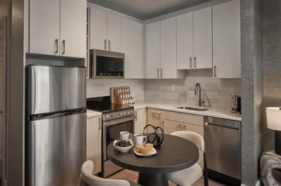 a kitchen with a table and a stainless steel refrigerator at Luxury Apartments by Hyatus Center City in Philadelphia