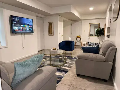 a living room with couches and a tv on a wall at Cosy Bedroom 6 minutes to EWR Prudential Hotels Pen station in Newark
