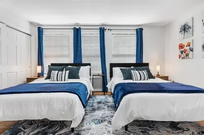 two beds in a room with blue curtains at NYC 20min, Sleeps 10, Free Parking, Patio in Bayonne