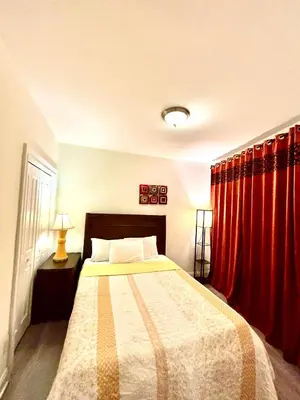 a bedroom with a bed with red curtains at Penn Station Room Motel Casa in Newark