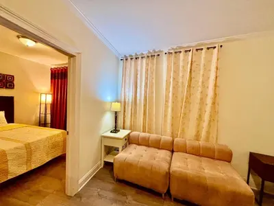 a bedroom with a bed and a window with a couch at Penn Station Room Motel Casa in Newark