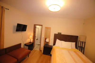 a bedroom with a bed and a couch and a television at Penn Station Room Motel Casa in Newark