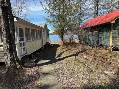 a house and a building with a red roof at Rustic Lakefront Cabin in Starrucca