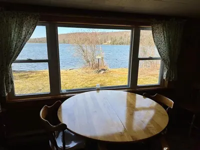 a table and chairs in a room with a window at Rustic Lakefront Cabin in Starrucca