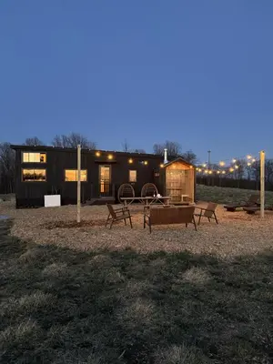 a tiny house with a picnic table and benches at night at The Retreat on the Ranch (INSANE VIEW) in Gap