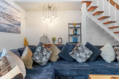 a living room with a blue couch with pillows at Spacious Game Room Seclusion Hot Tub and more in Long Pond