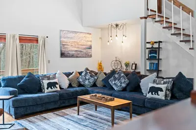 a living room with a blue couch with pillows at Spacious Game Room Seclusion Hot Tub and more in Long Pond