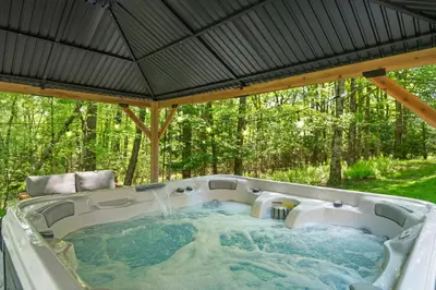 a hot tub in a backyard with a roof at Spacious Game Room Seclusion Hot Tub and more in Long Pond