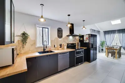 a kitchen with black cabinets and a black refrigerator at 3BR Home w Outdoor Fun Lake Fire Pit Games Grill in Tobyhanna
