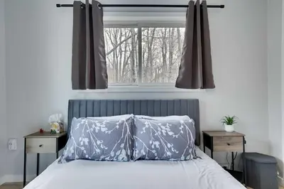a bed with two pillows in front of a window at 3BR Home w Outdoor Fun Lake Fire Pit Games Grill in Tobyhanna