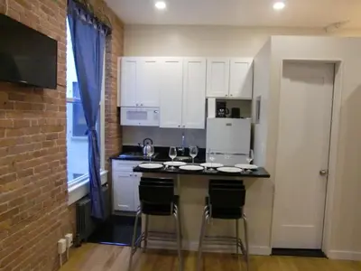 a kitchen with white cabinets and a counter with bar stools at Studios Midtown Manhattan in New York