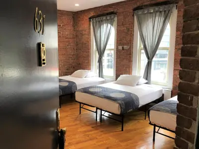 three beds in a room with two windows at Studios Midtown Manhattan in New York
