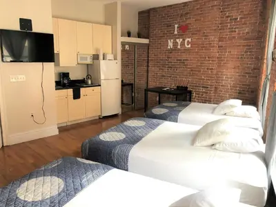 a hotel room with two beds and a kitchen at Studios Midtown Manhattan in New York