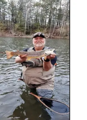 a man is holding a fish in the water at Rustic Cabin Rental on Family-Friendly Campsite near Harrisburg, Pennsylvania in Millmont