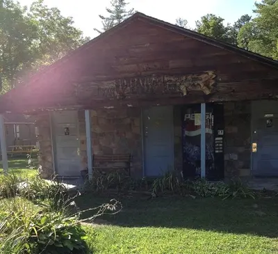 a stone house with blue doors and a porch at Rustic Cabin Rental on Family-Friendly Campsite near Harrisburg, Pennsylvania in Millmont