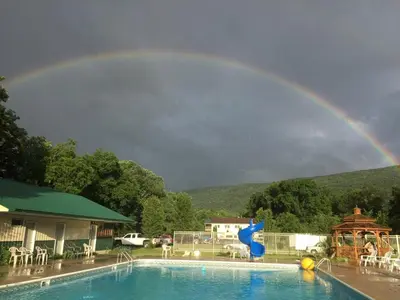 a rainbow over a swimming pool with a pool at Rustic Cabin Rental on Family-Friendly Campsite near Harrisburg, Pennsylvania in Millmont