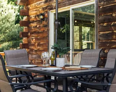 a wooden table on a porch with chairs and a tableablish at Incredible New York Cabin with a Spa and Movie Theater in Livingston Manor