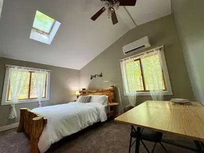 a bedroom with a bed and a table and windows at Cabin with Sauna Close to Skiing in Arrowhead Lake
