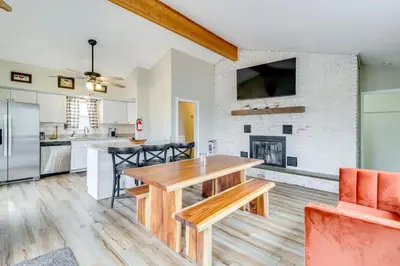 a kitchen and living room with a wooden table and a fireplace at Beach Access BBQ-Ready Poconos Family Getaway! in Blakeslee