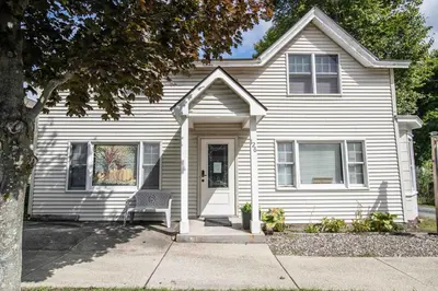 a white house with a chair in front of it at Heart of Historic Wurtsboro Suite 6 in Wurtsboro