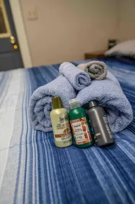 a bed with a blue towel and two bottles of shampoo at Heart of Historic Wurtsboro Suite 6 in Wurtsboro