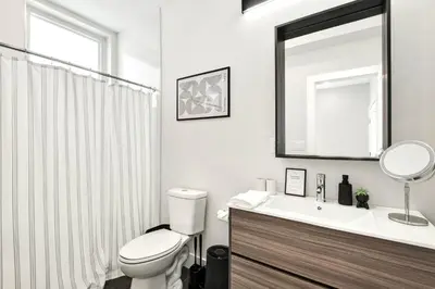 a bathroom with a toilet and a sink and a mirror at Spacious Center City 3BR 4BA with Arcade - Sleeps 8 in Philadelphia