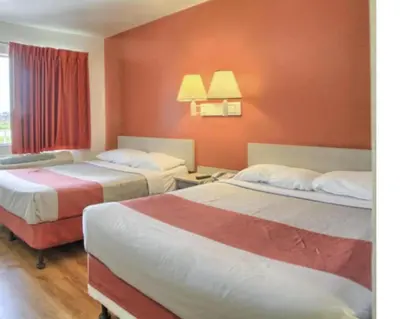 two beds in a hotel room with red walls at Cumberland Inn By OYO New Cumberland-Hershey South in New Cumberland