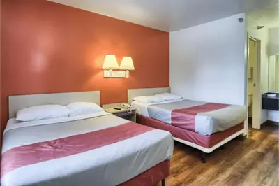 two beds in a hotel room with orange walls at Cumberland Inn By OYO New Cumberland-Hershey South in New Cumberland