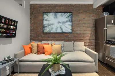 a living room with a couch and a brick wall at Explore NYC! Cozy 2BR in Prime Location in New York