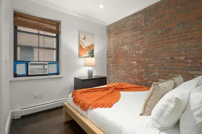 a bedroom with a brick wall and a bed at Explore NYC! Cozy 2BR in Prime Location in New York