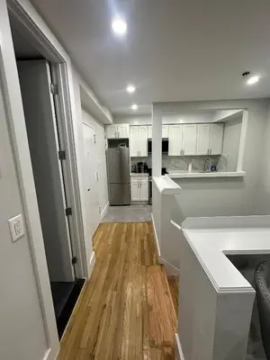 a kitchen with white cabinets and a wooden floor at The Gray Loft Escape NYC Edition. in New York