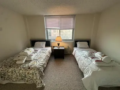 two twin beds in a room with a window at 1500 Locust Apartments Luxury Living in the Heart of Philadelphia in Philadelphia